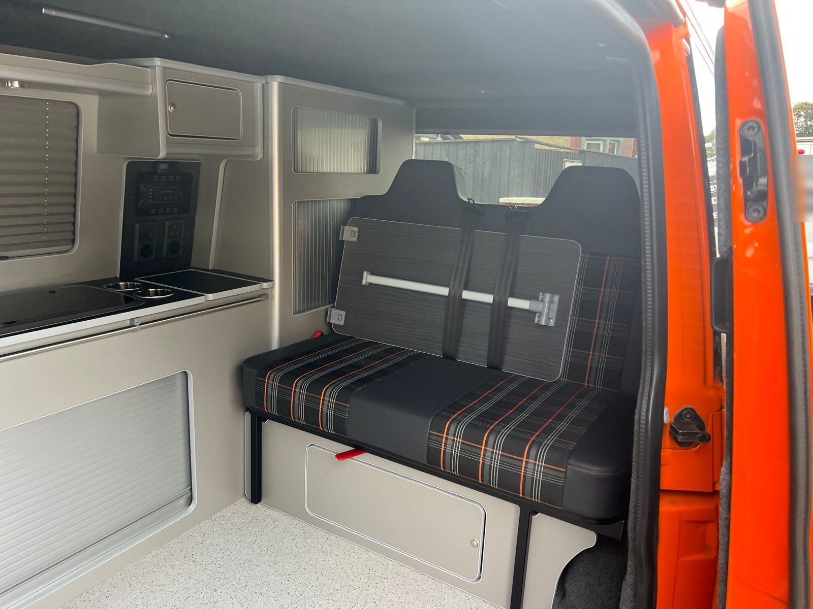 Seating and kitchen units inside the orange van conversion