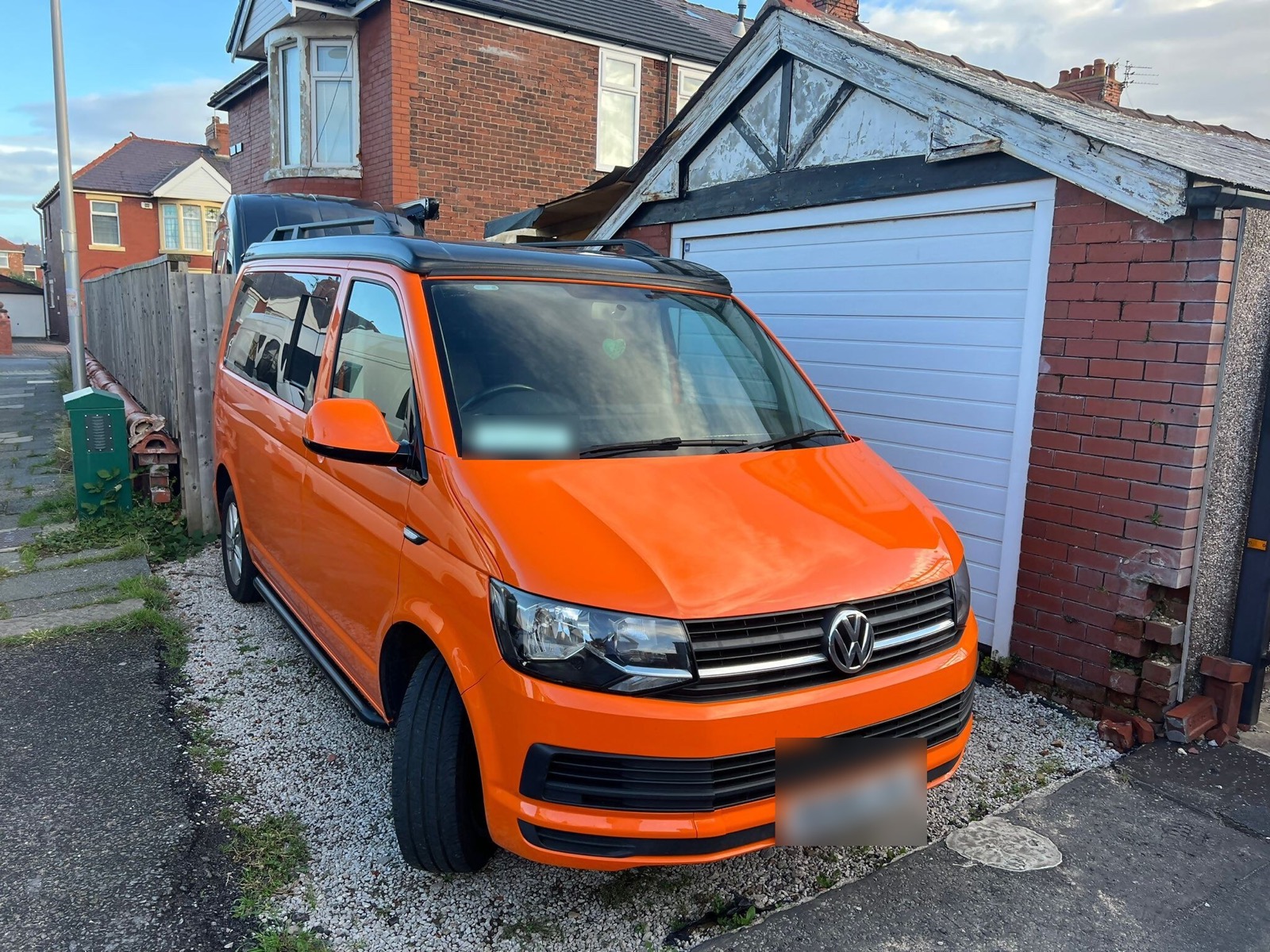 Converted orange van parked in front of a garage